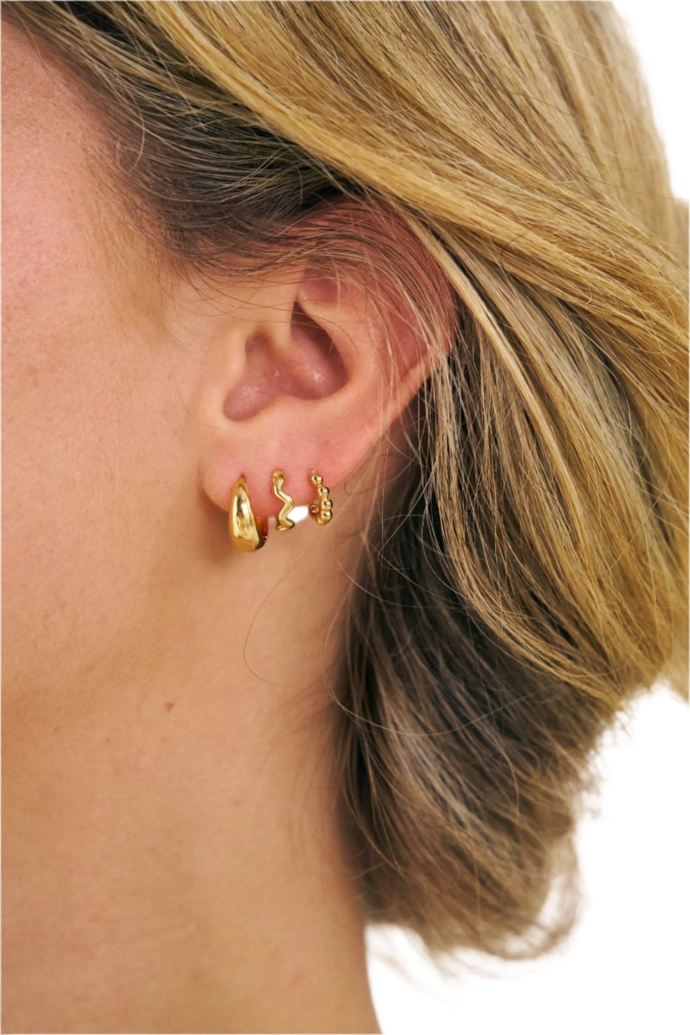 Girl wearing 3 18k gold filled huggie earrings 